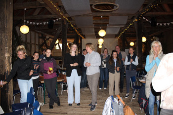 Gruppe von Personen steht in beleuchteter Fachwerkscheune