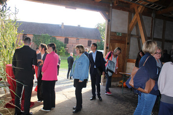 Personengruppen am Eingang einer Fachwerkscheune mit Blick nach draußen