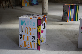 Papphocker mit Schriftzug im Dorf Orte für Jugend