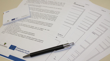Formulare liegen aufgefächert mit Stift und Notizzettel auf einem Tisch