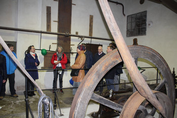Altes Antriebsrad einer Fabrik mit Besuchergruppe im Hintergrund