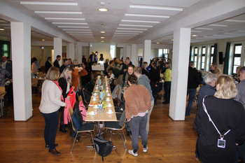 Teilnehmer Arbeitskreis an langer Tafel mit Blick zum Podium