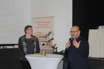 Eine Frau und ein Mann an einem Stehtisch in Redesituation
