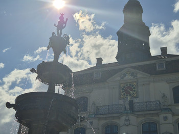 Springbrunnen mit Lüneburger Rathaus und Sonne im Hintergrund 