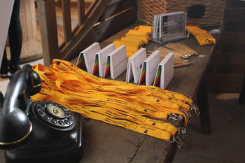 Schwarzes Wählscheibentelefon, gelbe Schlüsselbänder, Notizzettel, Stifte und weiteres Werbematerial