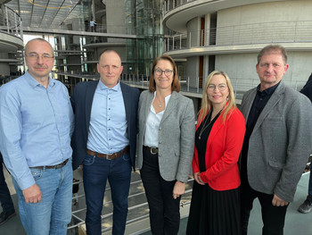 Gruppenbild mit 3 männlichen und 2 weiblichen Personen im Innenbereich des Deutschen Bundestages