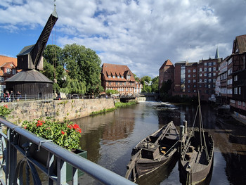 Wasserkanal mit zwei alten Holzbooten umgeben von Altstadthäusern und einem historischen Holzkran