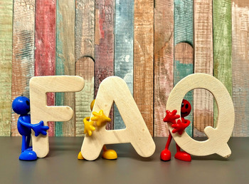 Holz-Buchstaben FAQ, die von bunten Figuren gehalten werden